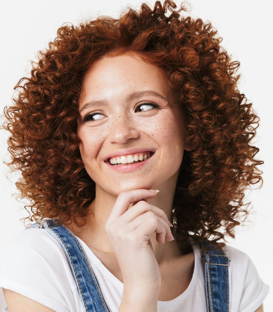 Portrait einer Frau, die zur Seite schaut, weites Lächeln, Finger am Kinn